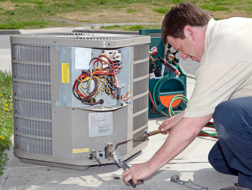 R.F. Ohl technician performing AC repair and tune-up service on a residential cooling unit